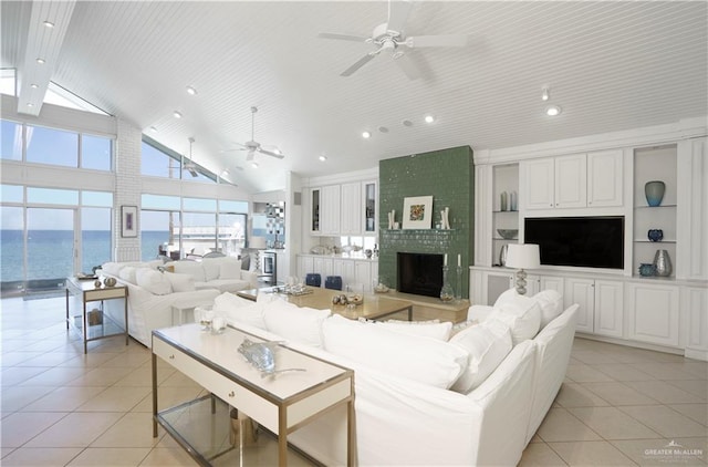 tiled living room featuring built in shelves, a wealth of natural light, a water view, and high vaulted ceiling