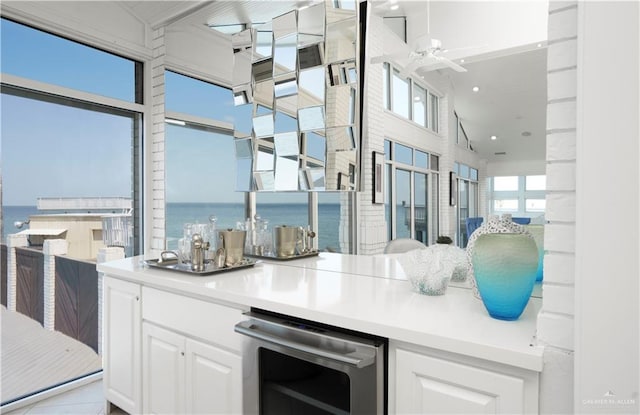 kitchen featuring white cabinets, ceiling fan, a water view, and beverage cooler