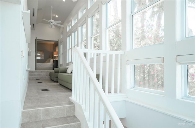 stairway with tile patterned floors, high vaulted ceiling, ceiling fan, and a healthy amount of sunlight