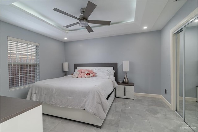 bedroom featuring ceiling fan, a tray ceiling, and a closet