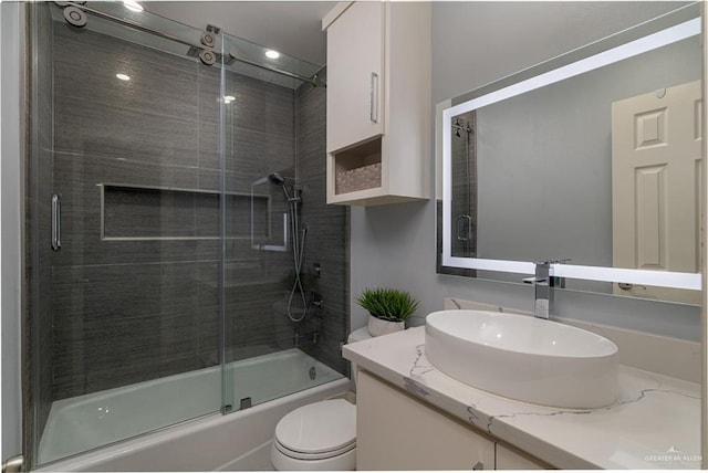 full bathroom featuring toilet, bath / shower combo with glass door, and vanity