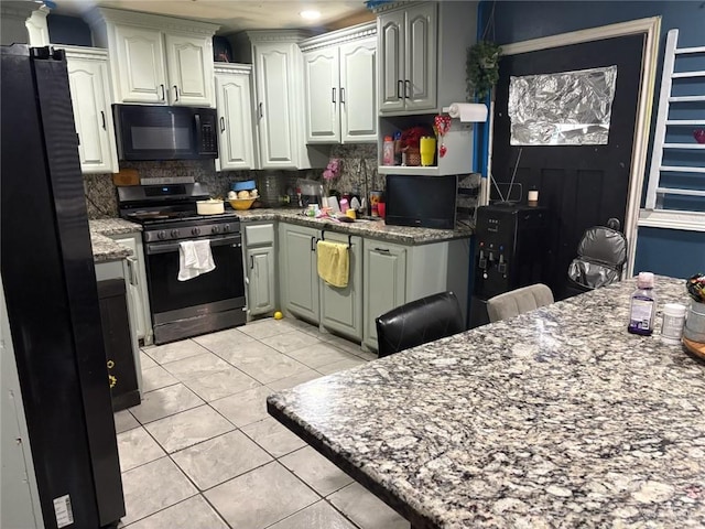 609 S 24th St, Donna, TX 78537 - kitchen with black appliances, tasteful backsplash, light tile patterned floors, and light stone countertops