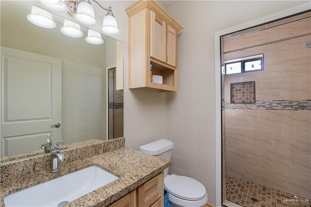 bathroom featuring tiled shower, vanity, and toilet