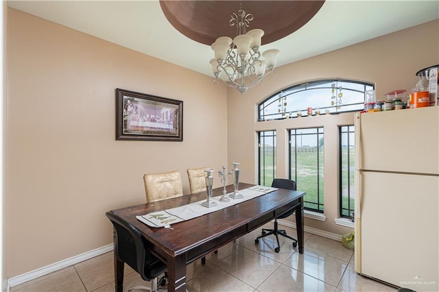 dining area featuring a raised ceiling, an inviting chandelier, and light tile patterned flooring