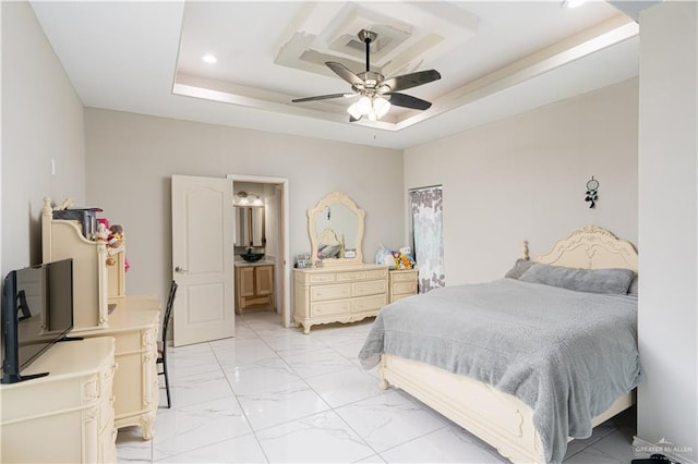 bedroom with ceiling fan, connected bathroom, and a tray ceiling