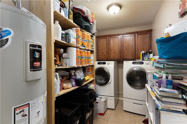 washroom with washing machine and dryer, electric water heater, light tile patterned floors, and cabinets