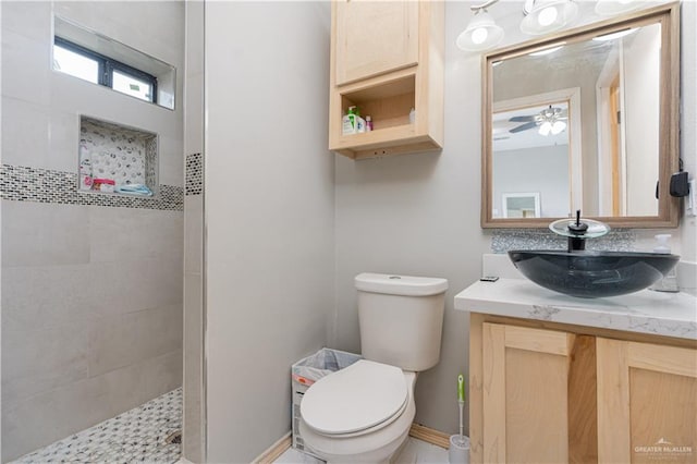 bathroom featuring vanity, ceiling fan, toilet, and tiled shower