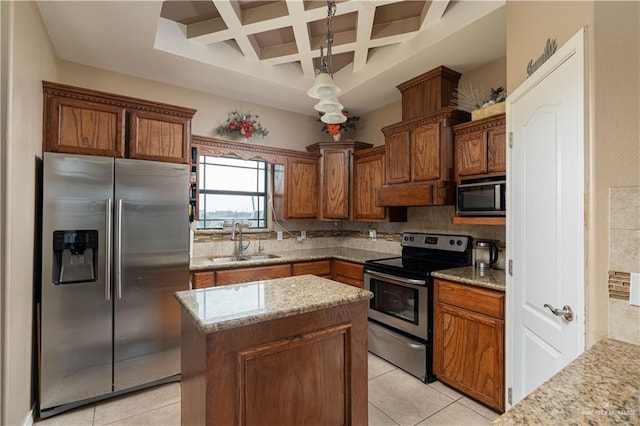 kitchen featuring appliances with stainless steel finishes, coffered ceiling, sink, decorative light fixtures, and a kitchen island