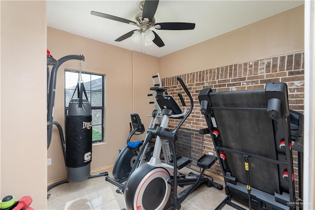 exercise room featuring ceiling fan and brick wall