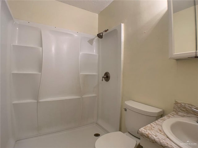 bathroom featuring toilet, a shower, and a sink