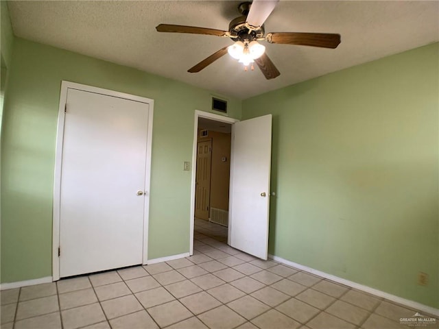 unfurnished bedroom featuring ceiling fan, baseboards, a textured ceiling, and light tile patterned flooring