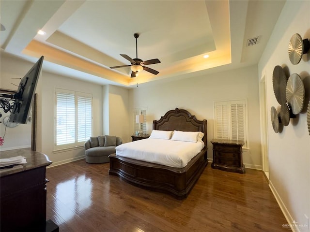 bedroom with a raised ceiling, ceiling fan, and dark wood-type flooring