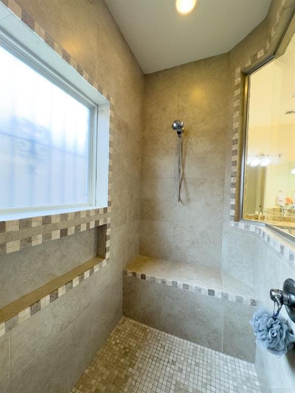 bathroom with a tile shower and tile walls