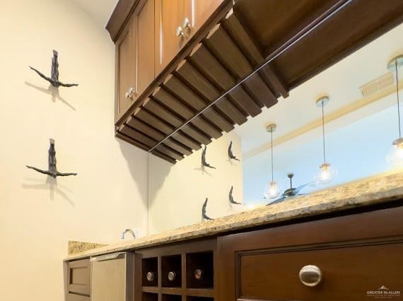 bar featuring decorative light fixtures and light stone counters