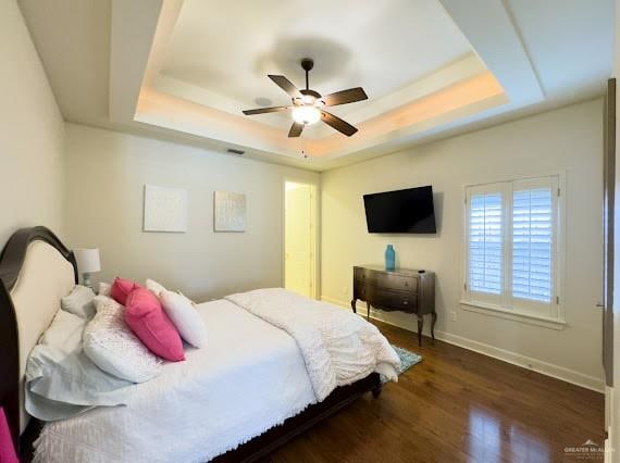 bedroom featuring a raised ceiling, ceiling fan, and dark hardwood / wood-style floors