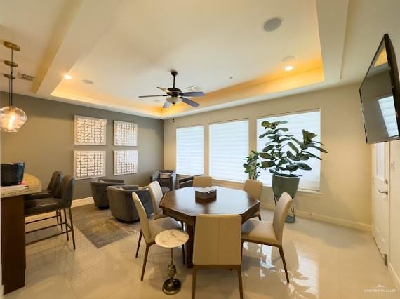 dining space with a raised ceiling and ceiling fan