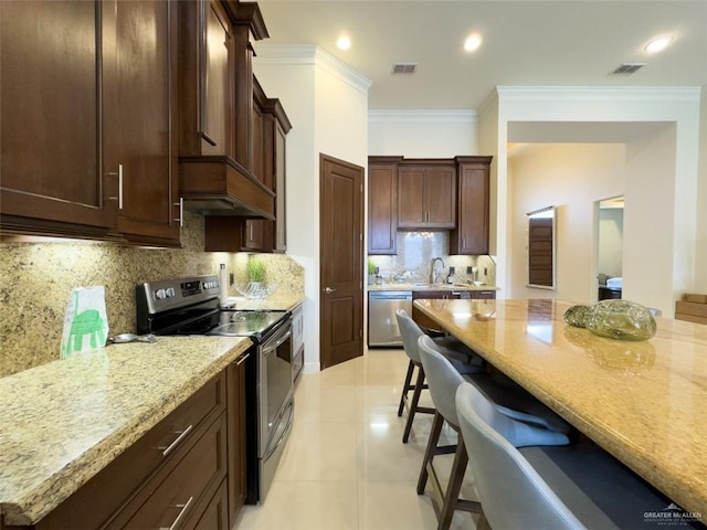 kitchen featuring light stone countertops, appliances with stainless steel finishes, decorative backsplash, and ornamental molding