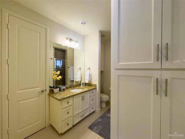 bathroom with toilet, vanity, and tile patterned floors