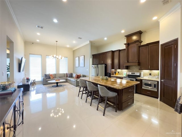 kitchen featuring tasteful backsplash, a chandelier, a kitchen bar, a kitchen island, and appliances with stainless steel finishes