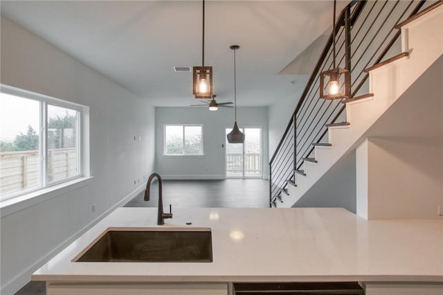 kitchen with pendant lighting, ceiling fan, hardwood / wood-style flooring, and sink