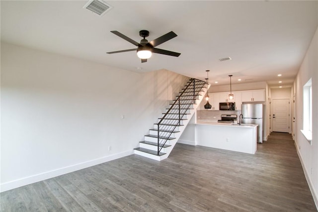 unfurnished living room featuring dark hardwood / wood-style flooring, ceiling fan, and sink