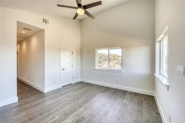 empty room with ceiling fan, dark hardwood / wood-style floors, and plenty of natural light