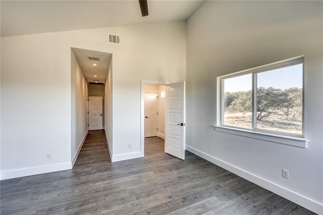 unfurnished bedroom with high vaulted ceiling and dark wood-type flooring