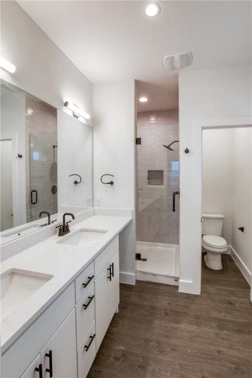 bathroom with a shower with door, dual sinks, large vanity, and hardwood / wood-style flooring