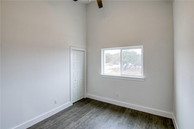 spare room with dark hardwood / wood-style flooring, ceiling fan, and a towering ceiling