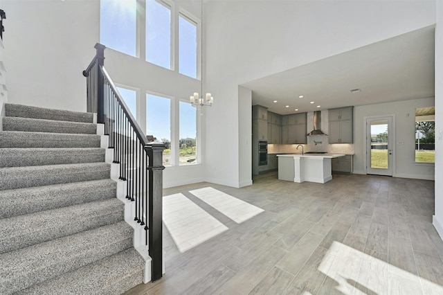 staircase featuring a notable chandelier, light hardwood / wood-style floors, and sink