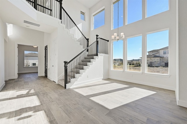 staircase featuring a high ceiling, a notable chandelier, and light wood-type flooring