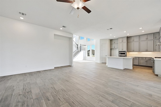 kitchen with a center island, gray cabinetry, ceiling fan, and light wood-type flooring