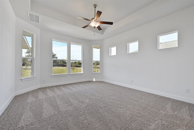 spare room featuring light colored carpet, a tray ceiling, and ceiling fan