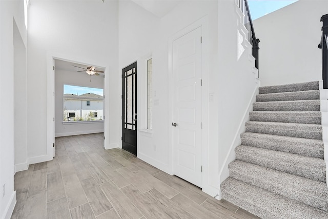 stairs featuring light hardwood / wood-style floors and ceiling fan