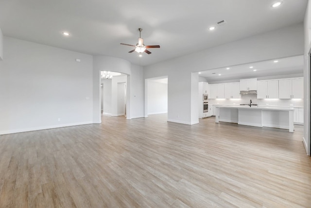 unfurnished living room featuring sink, light hardwood / wood-style floors, and ceiling fan with notable chandelier