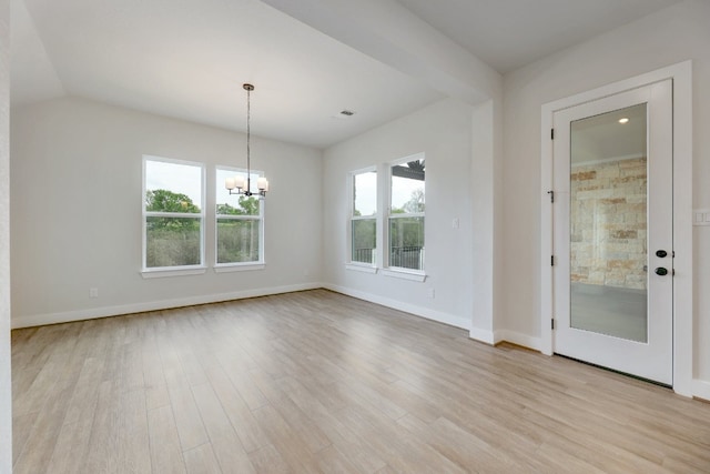 spare room featuring vaulted ceiling, a notable chandelier, and light hardwood / wood-style floors