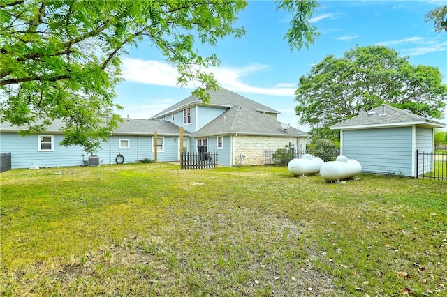 rear view of house featuring central AC unit and a yard