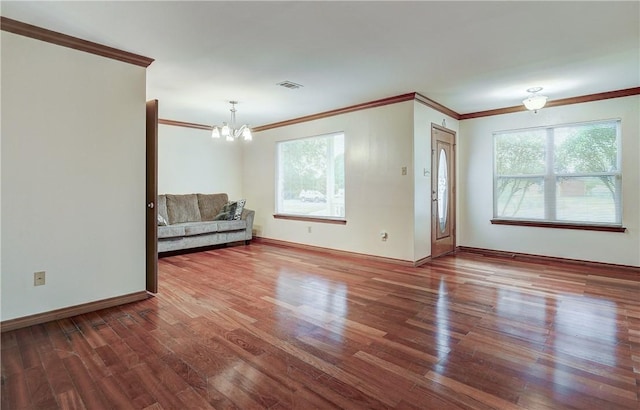 unfurnished room with crown molding, hardwood / wood-style floors, and an inviting chandelier