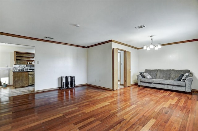 living room with an inviting chandelier, ornamental molding, and hardwood / wood-style floors