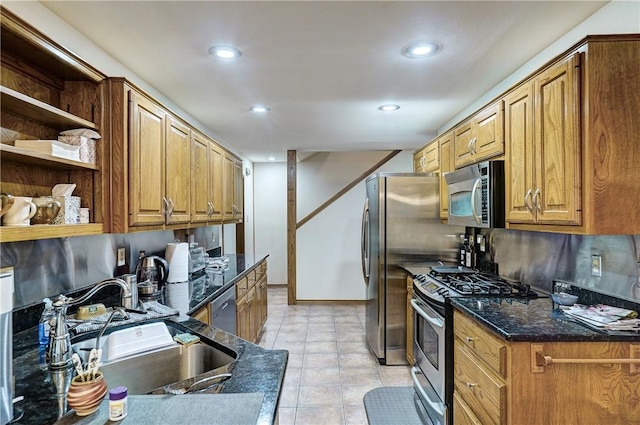 kitchen with sink, light tile floors, stainless steel appliances, and dark stone countertops