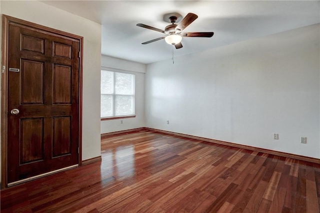 spare room with dark hardwood / wood-style flooring and ceiling fan