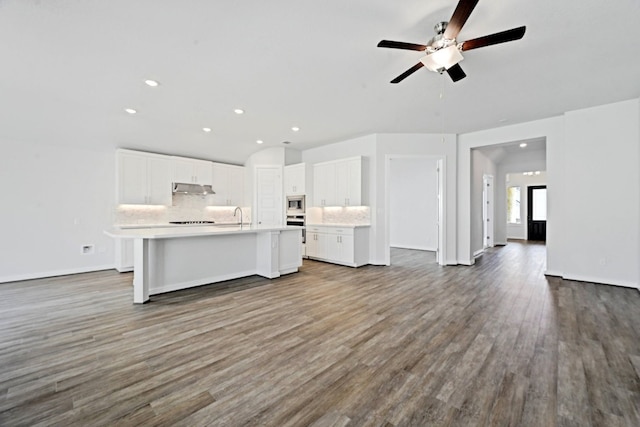 kitchen featuring ceiling fan, backsplash, hardwood / wood-style floors, an island with sink, and white cabinets