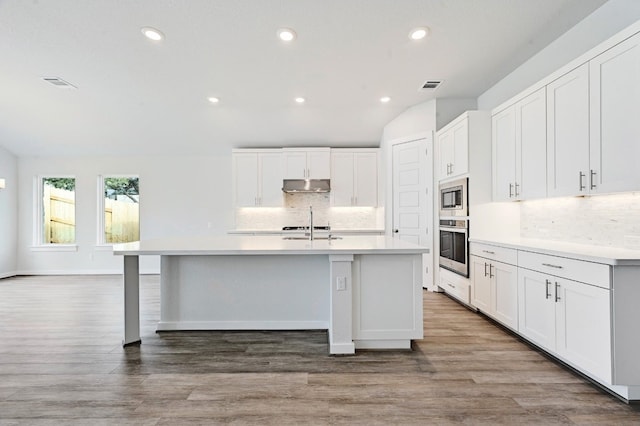 kitchen featuring backsplash, stainless steel appliances, hardwood / wood-style floors, and white cabinetry