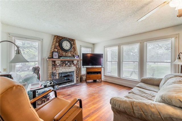 living room with a fireplace, a wealth of natural light, and light wood-type flooring