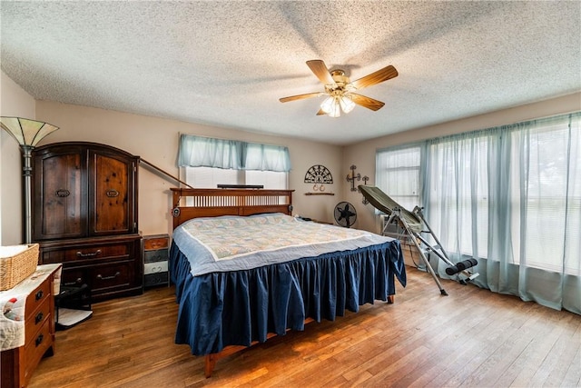 bedroom featuring dark hardwood / wood-style flooring, ceiling fan, and a textured ceiling