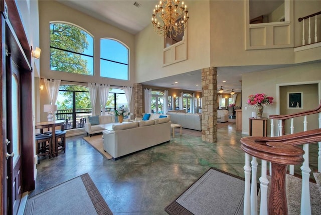 living room with ornate columns, tile floors, ceiling fan with notable chandelier, and a towering ceiling