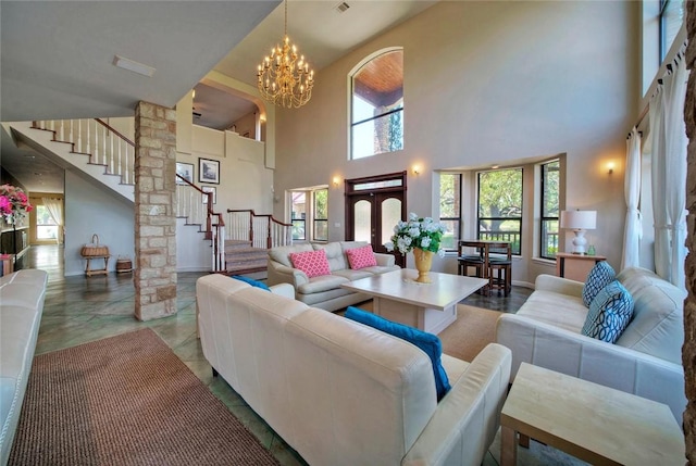 living room featuring a towering ceiling, light tile floors, a chandelier, and french doors