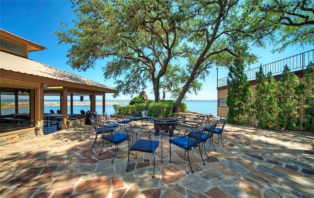 view of terrace with an outdoor fire pit and a water view