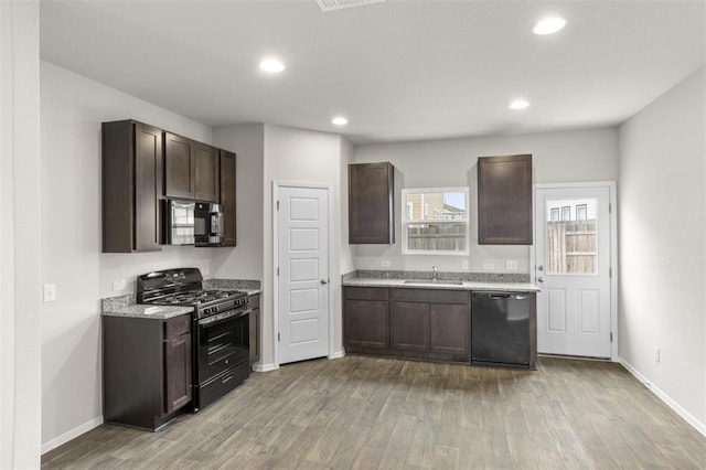 kitchen featuring black appliances, dark brown cabinetry, light wood-type flooring, and sink