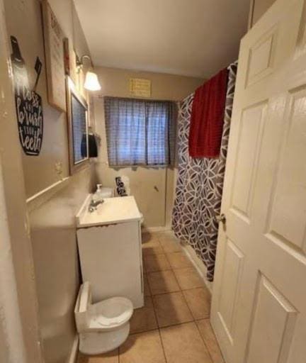 bathroom with toilet, tile flooring, and vanity